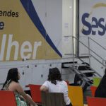 Unidade móvel Sesc Saúde Mulher, com pessoas esperando atendimento.
