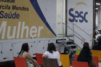Unidade móvel Sesc Saúde Mulher, com pessoas esperando atendimento.