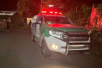 Viatura da Polícia Militar no local de uma ocorrência à noite, com luzes de emergência acesas.
