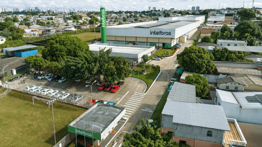 Vista aérea da fábrica da Intelbras em Manaus, com carros estacionados e prédios ao fundo.
