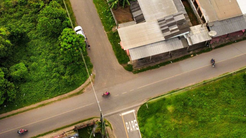 Vista aérea de uma estrada com motos e vegetação exuberante.