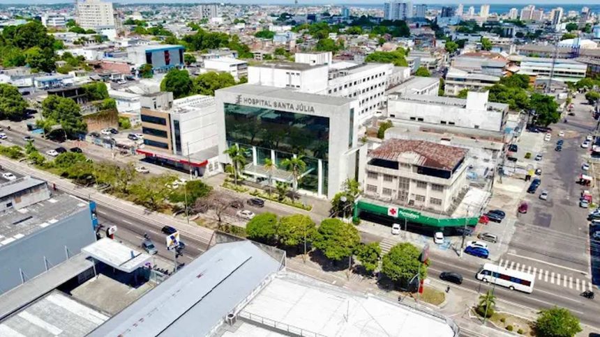 Vista aérea do Hospital Santa Júlia em Manaus, com prédios, ruas e vegetação.