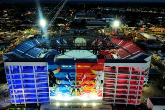 Vista noturna do Bumbódromo em Parintins, Amazonas, com iluminação colorida e detalhes da arquitetura.