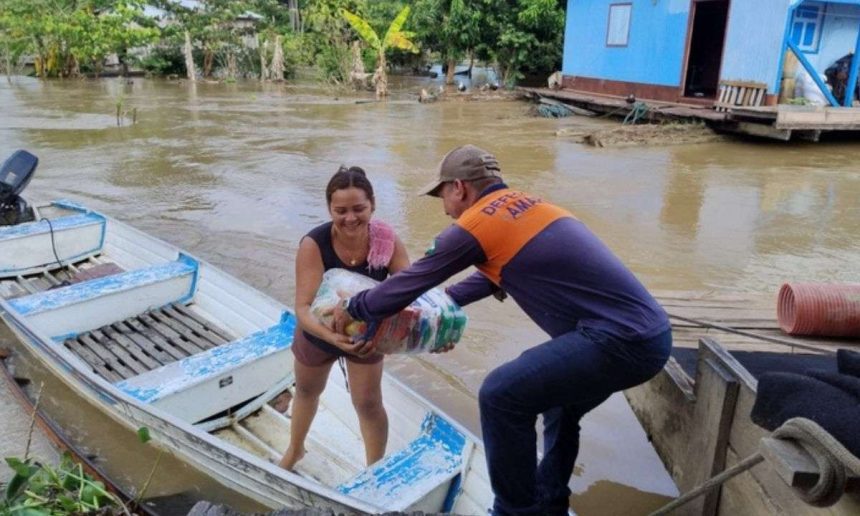 Voluntário entrega cestas básicas para vítima de enchente no Amazonas.