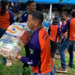 Voluntários carregando sacos de alimentos para vítimas da cheia no Amazonas.