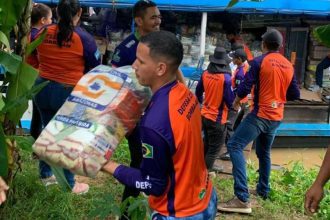 Voluntários carregando sacos de alimentos para vítimas da cheia no Amazonas.