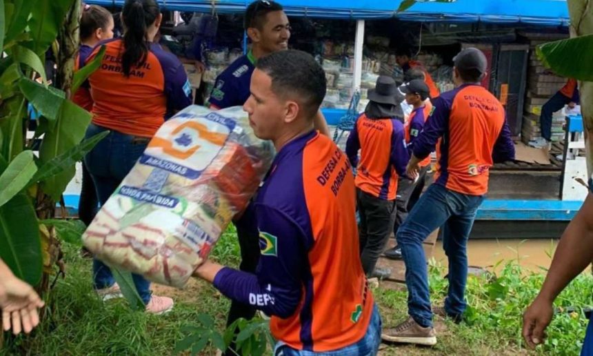 Voluntários carregando sacos de alimentos para vÃtimas da cheia no Amazonas.