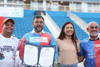 Wilson Lima em evento sobre editais culturais, com outras pessoas sorrindo e segurando documentos.