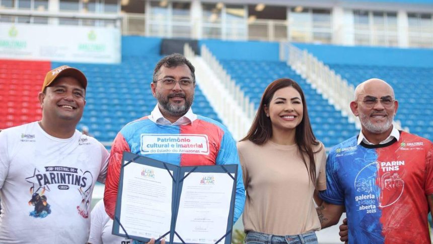 Wilson Lima em evento sobre editais culturais, com outras pessoas sorrindo e segurando documentos.