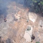 Ação de combate ao garimpo ilegal em área de floresta, com helicóptero e fogo.
