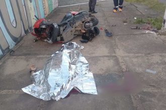 Acidente de moto com vítima fatal: moto destruída e corpo coberto.