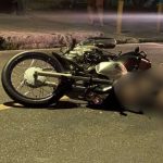 Acidente de trânsito com motocicleta na rua à noite.