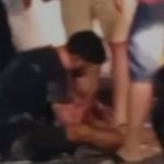 Acidente de trânsito com motociclista e carro. Pessoas ao redor do ferido.