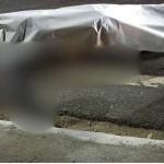 Acidente de trânsito com vítima fatal, coberto por um lençol na rua.