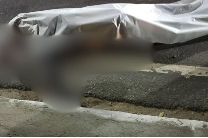 Acidente de trânsito com vítima fatal, coberto por um lençol na rua.