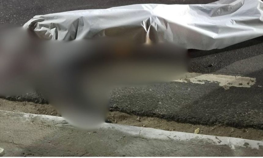 Acidente de trânsito com vítima fatal, coberto por um lençol na rua.