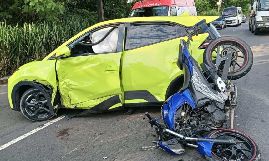 Acidente grave: carro amarelo danificado e moto azul destruída na pista.