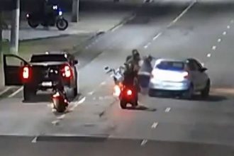 Agressão a policial federal em cena de rua à noite, com motos e carros.