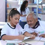 Alunos e professor em sala de aula, com foco em atividade de escrita e estudo.