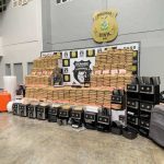 Apreensão de drogas em uma delegacia. Pacotes de drogas empilhados, eletrodomésticos e malas.