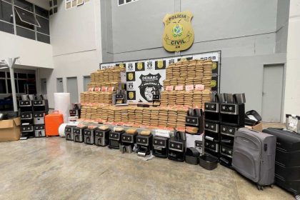 Apreensão de drogas em uma delegacia. Pacotes de drogas empilhados, eletrodomésticos e malas.