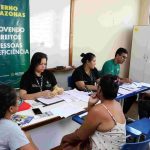 Atendimento a pessoas com deficiência em órgão público, com banner "Promovendo os direitos das pessoas com deficiência".