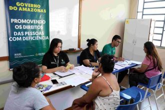 Atendimento a pessoas com deficiência em órgão público, com banner "Promovendo os direitos das pessoas com deficiência".
