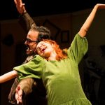 Atrizes em cena teatral com figurino e expressão dramática.