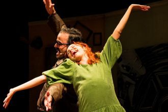 Atrizes em cena teatral com figurino e expressão dramática.