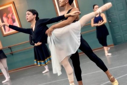 Bailarinos em ensaio de balé no palco, com foco em uma dupla em pose.