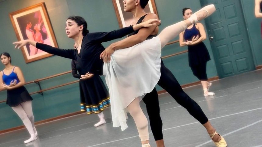 Bailarinos em ensaio de balé no palco, com foco em uma dupla em pose.