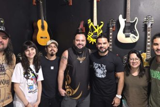 Banda e equipe do Critical Age posam para foto em estúdio com guitarras.
