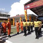 Bombeiros em frente a um quartel, com viatura de combate a incêndios e autoridades.