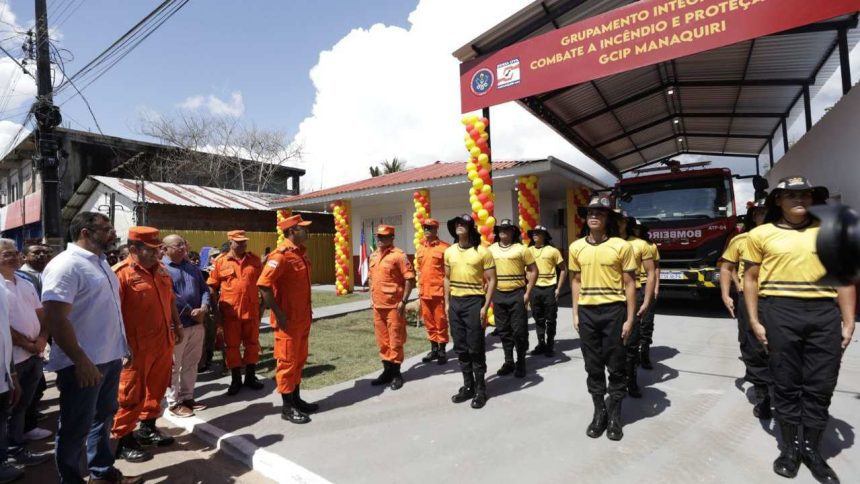 Bombeiros em frente a um quartel, com viatura de combate a incêndios e autoridades.