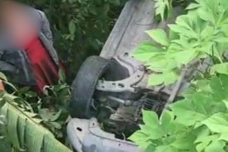 Carro tombado em barranco após motorista de aplicativo perder o controle, área de mata.