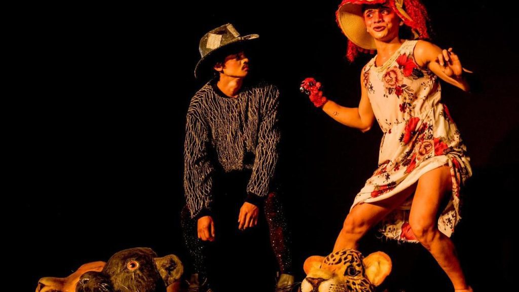 Cena teatral com figurinos extravagantes, possivelmente sobre Rita Lee.