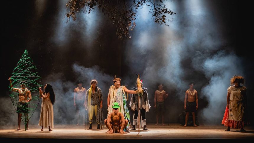 Cena teatral com personagens em figurinos coloridos, representando a mitologia Tukano.