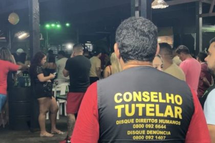 Conselheiro Tutelar em ação em ambiente noturno, lugares conhecidos como adegas, com pessoas ao fundo. Discagem para direitos humanos e denúncia.