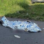 Corpo coberto em estrada após homicídio.