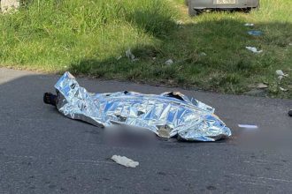 Corpo coberto em estrada após homicídio.