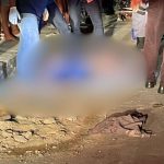 Corpo de homem coberto na rua, cena de crime com pessoas ao redor.