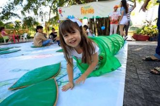Criança sorrindo em festival de férias, dentro de túnel verde