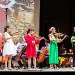 Crianças do Centro Suzuki se apresentam em recital no Palácio da Justiça, tocando violino.