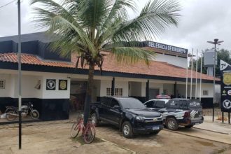Delegacia de Eirunepé com viaturas e árvore.