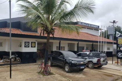 Delegacia de Eirunepé com viaturas e árvore.