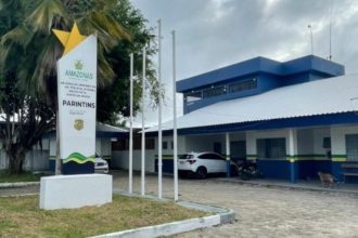 Delegacia de Polícia em Parintins, Amazonas, Brasil. Fachada com placa e carros estacionados.