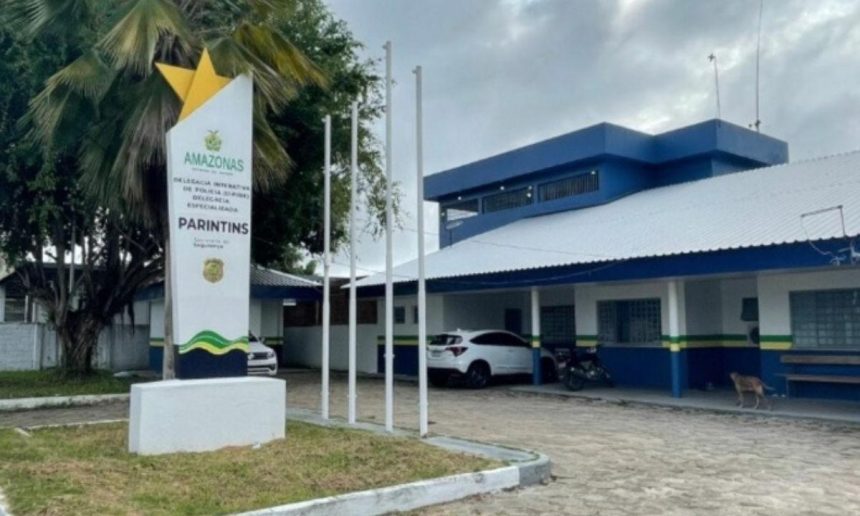 Delegacia de Polícia em Parintins, Amazonas, Brasil. Fachada com placa e carros estacionados.