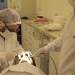 Dentistas realizando procedimento odontológico em paciente no Sesc.