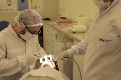 Dentistas realizando procedimento odontológico em paciente no Sesc.
