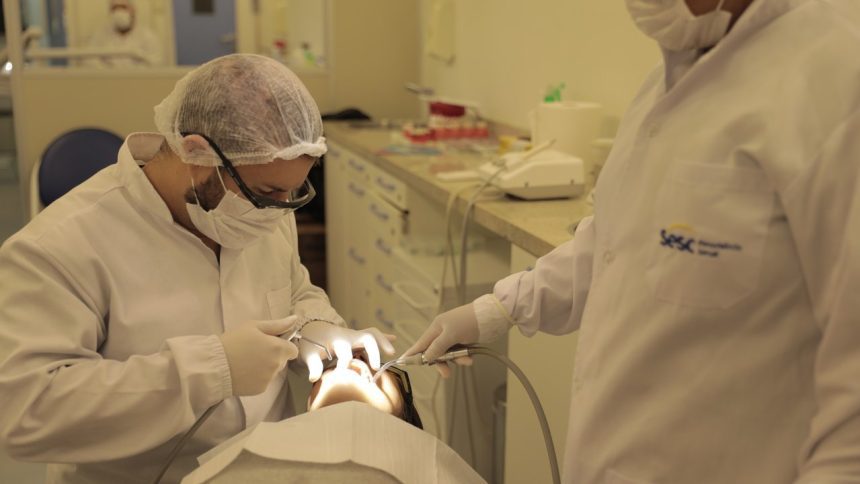 Dentistas realizando procedimento odontológico em paciente no Sesc.